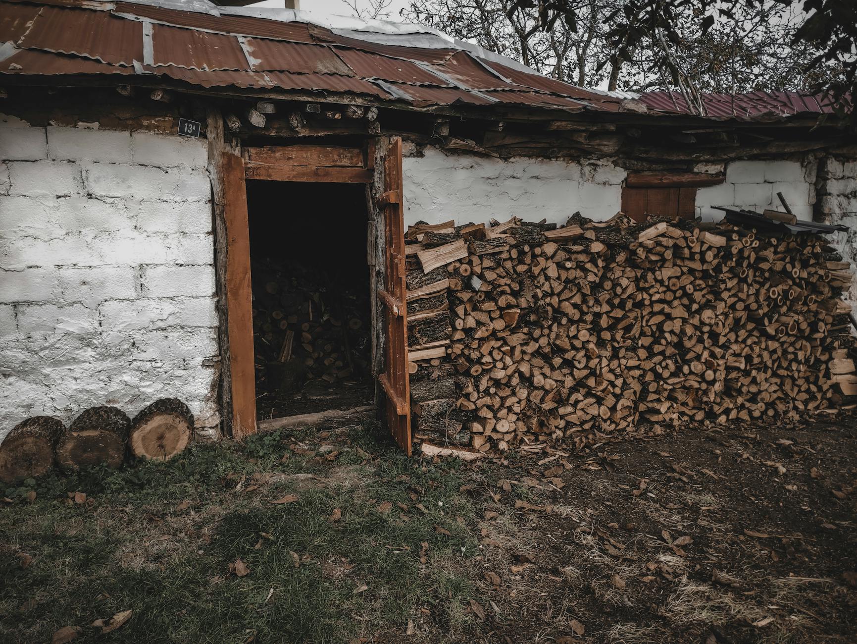 Stos drewna kominkowego przy otwartych drzwiach szopy na zewnątrz