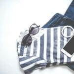 Płaskie ujęcie casualowego zestawu: pasek top, jeansy, okulary i smartfon